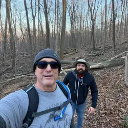 Thad and Ando hiking through bare winter woods on a trail.