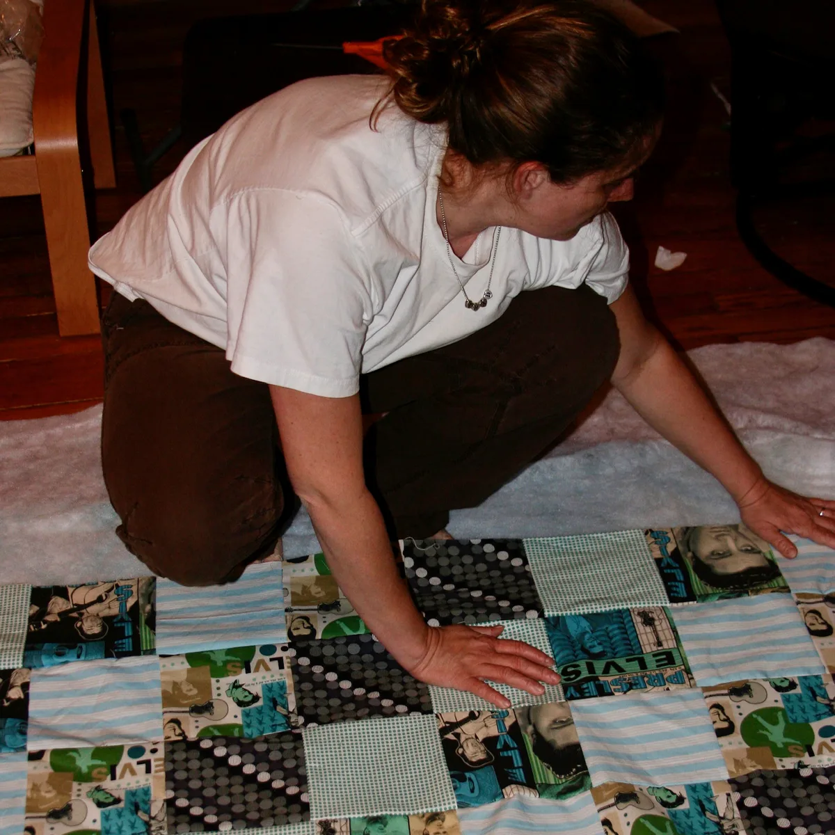Jolynn kneeling on the floor arranging a patchwork quilt project.
